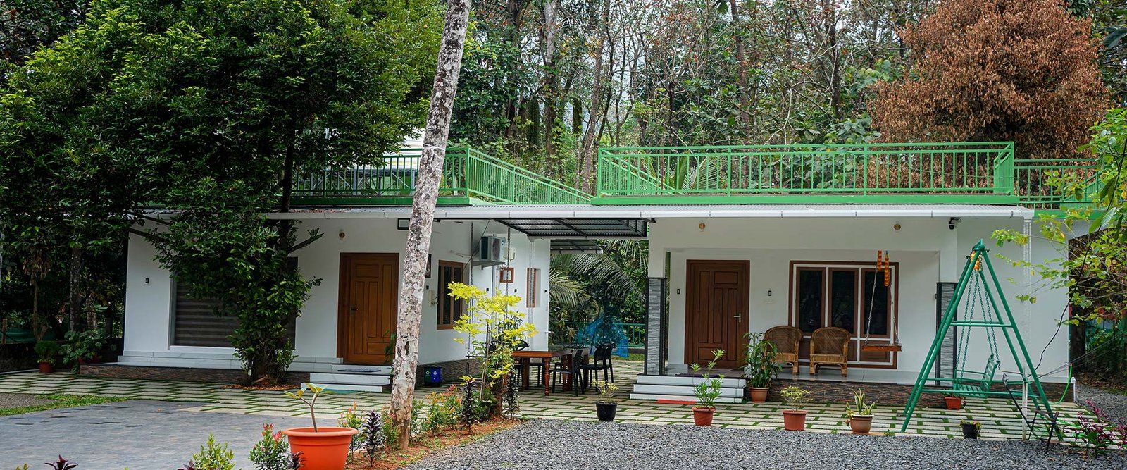 The white Jungle Bird house with its green terrace railings among the trees