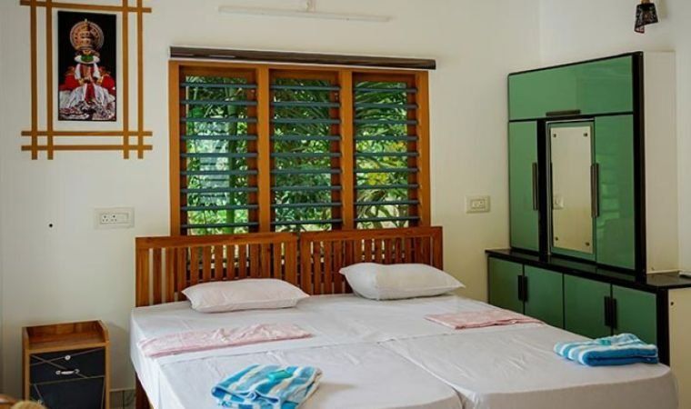 A Jungle Bird Resorts room with a Kathakali mask on the wall